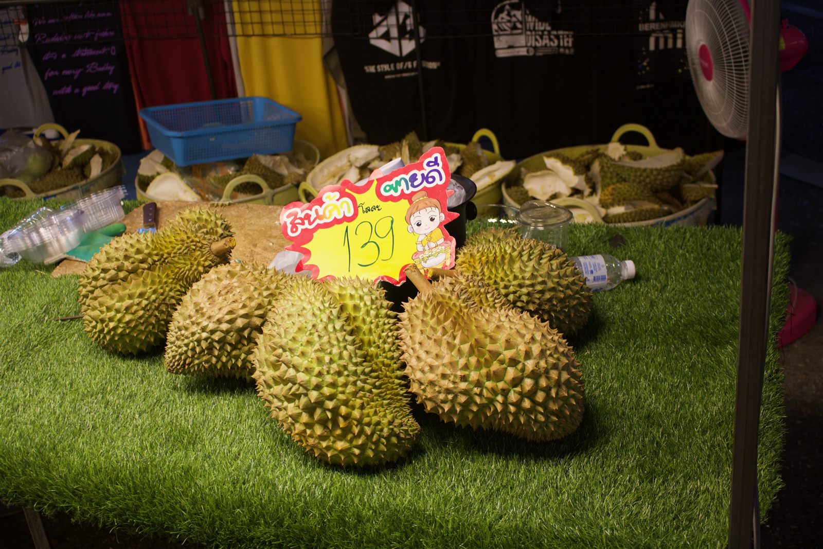 Street Food & Tuk-Tuk — whole durians piled up at a market stall